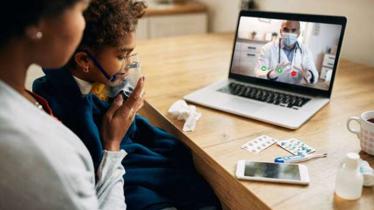 African American family doctor explaining online the procedure of inhaling therapy to mother and daughter at home during coronavirus pandemic.